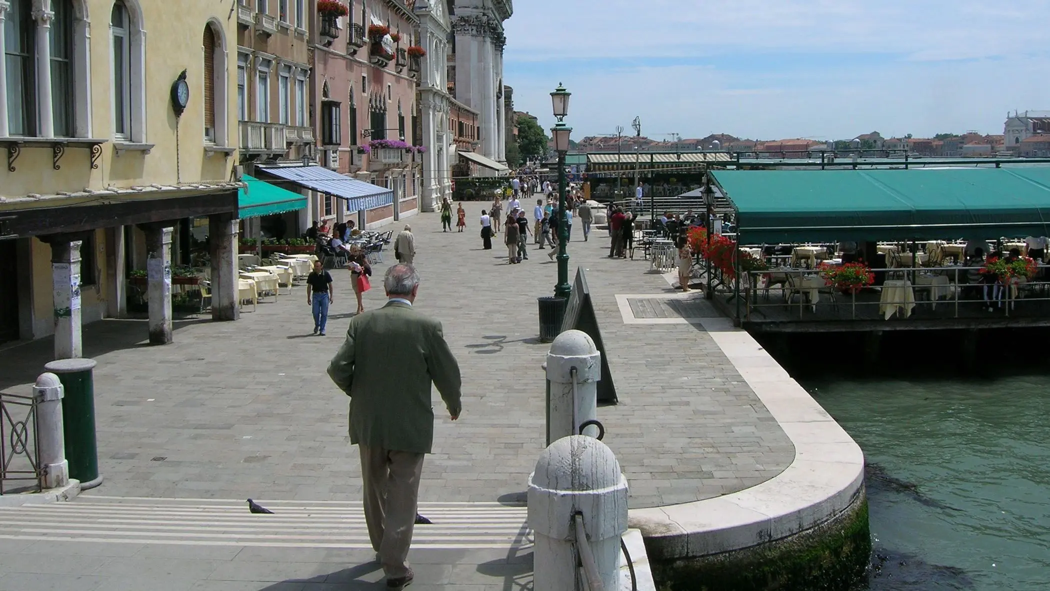 In the foreground, a man walking along a promenade.