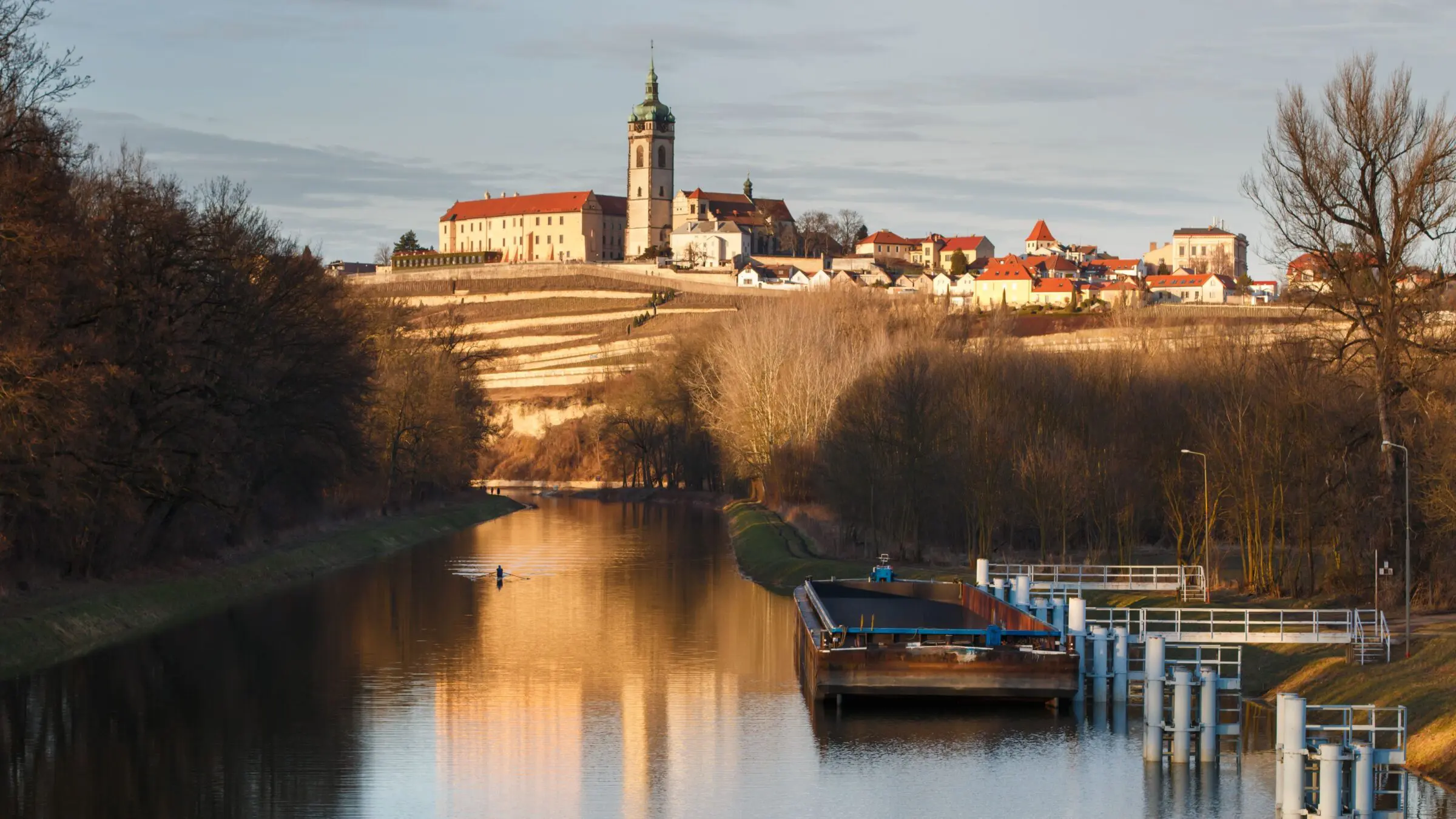 A quaint town on a hill in the background and a river in the foreground.
