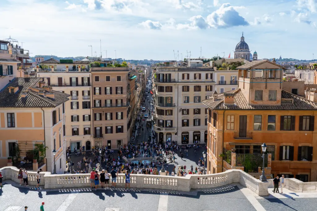 View from the Spanish Steps overlooking Piazza di Spagna and Via dei Condotti in Rome, with crowds of tourists and historic buildings
