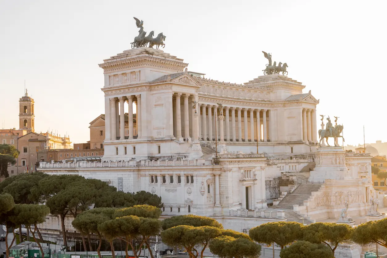 Sunlit view of the Altare della Patria, also known as the Victor Emmanuel II National Monument, in Rome, featuring neoclassical architecture and bronze chariots on the rooftop