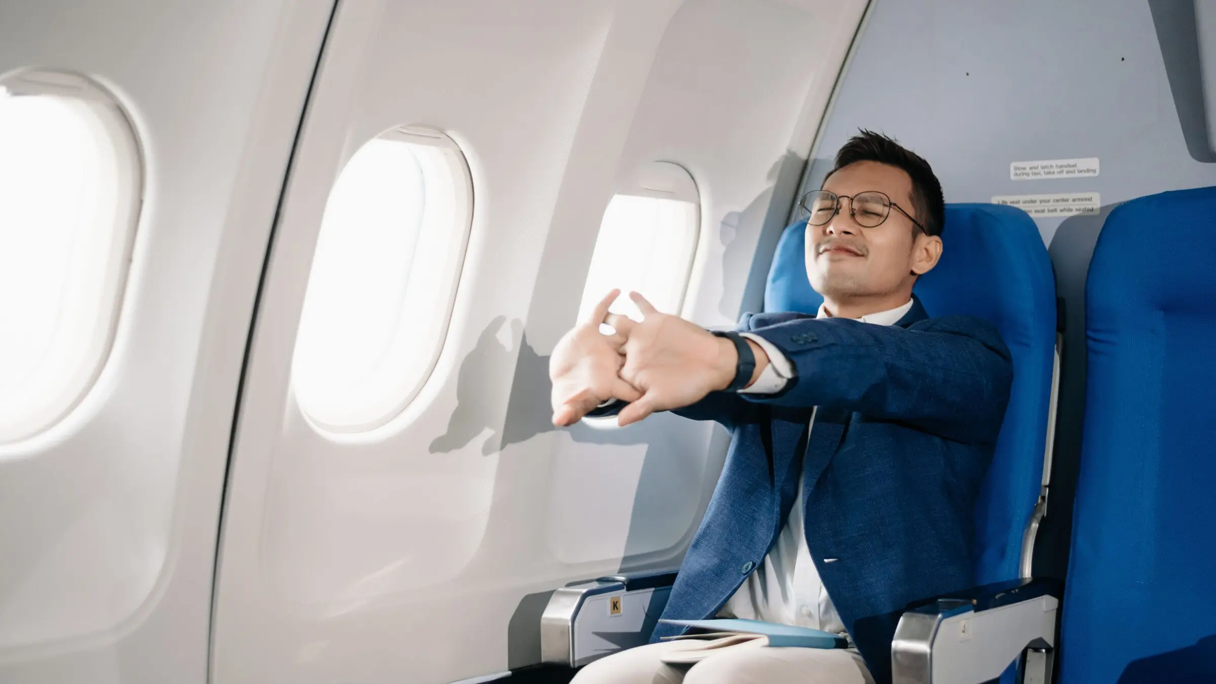 A man stretching his arms during a flight.