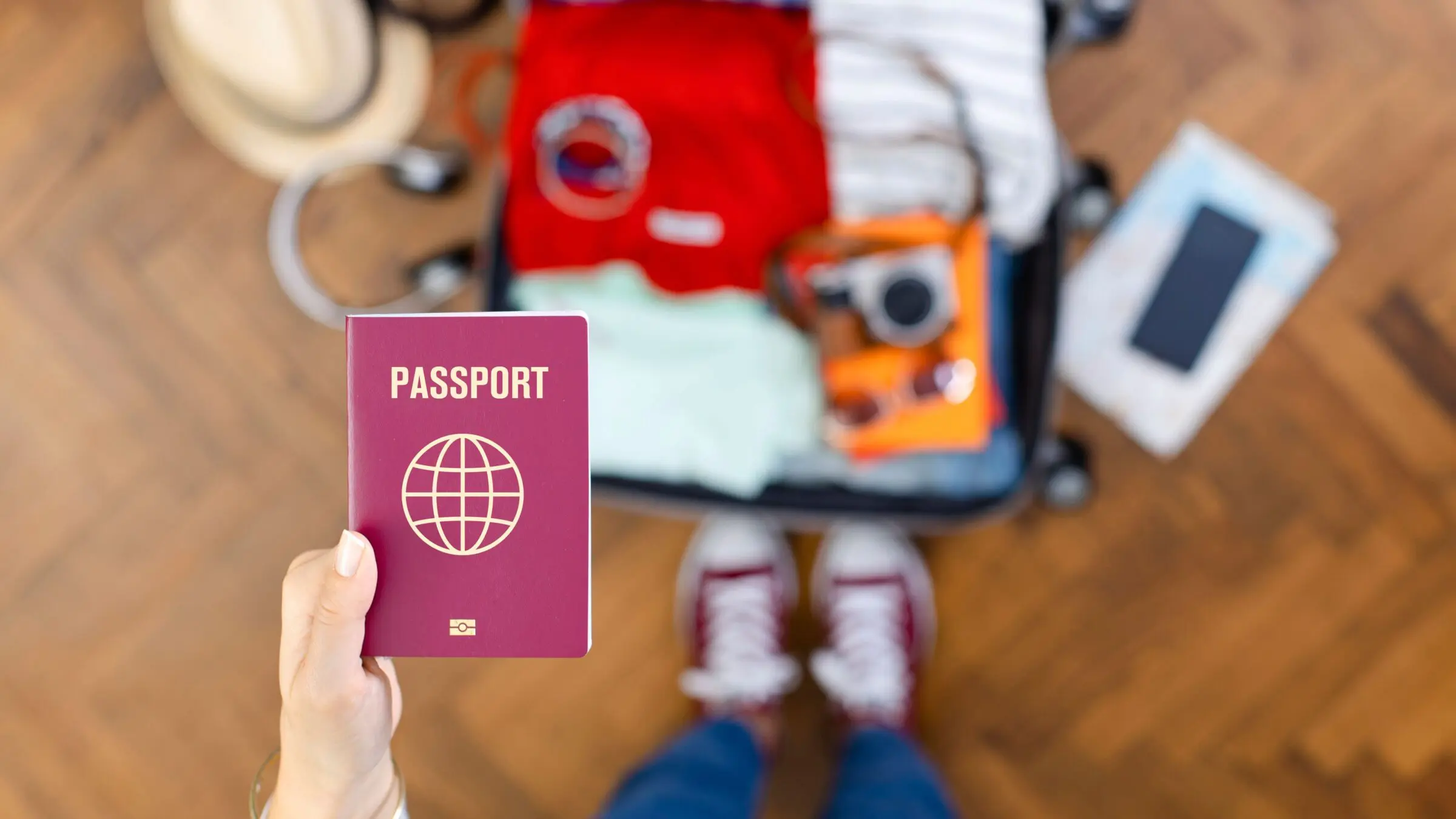 A woman is holding a passport over an open suitcase.