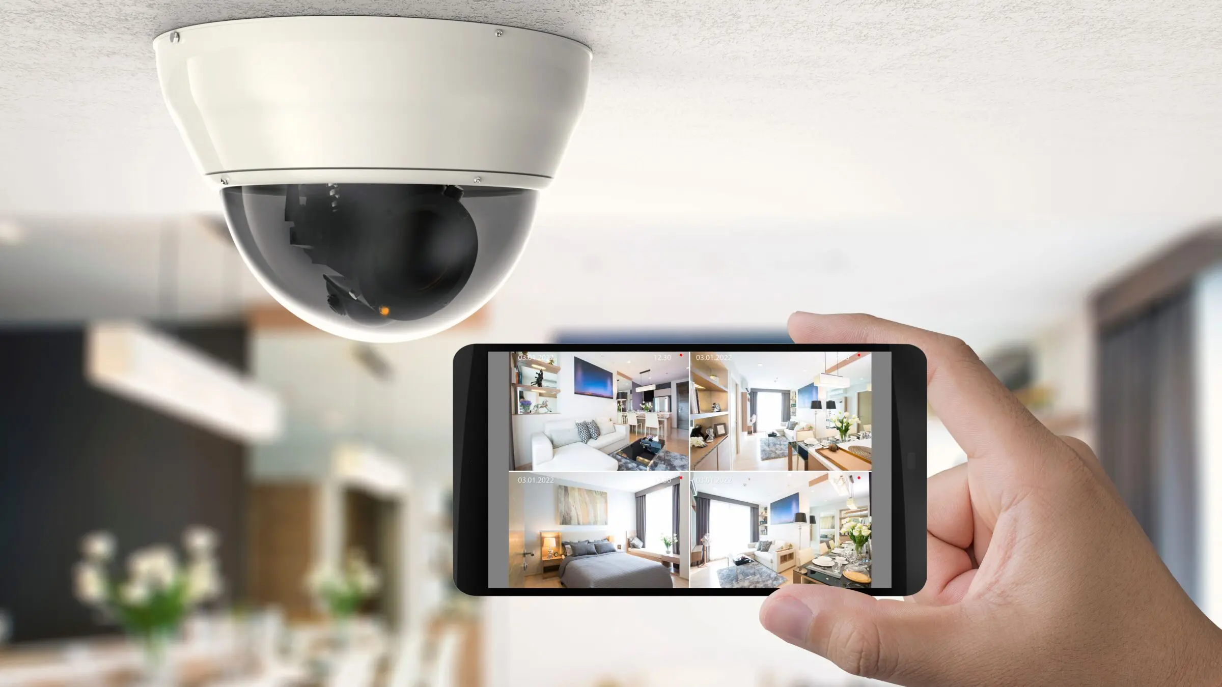 A hand holding a smartphone with security camera snapshots on the screen.