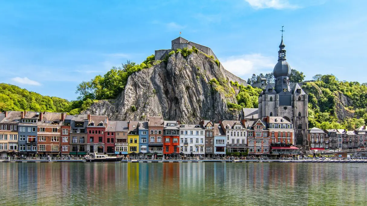 Colorful buildings and a citadel along the Meuse River in Dinant, Wallonia, one of the best places to visit in Belgium.