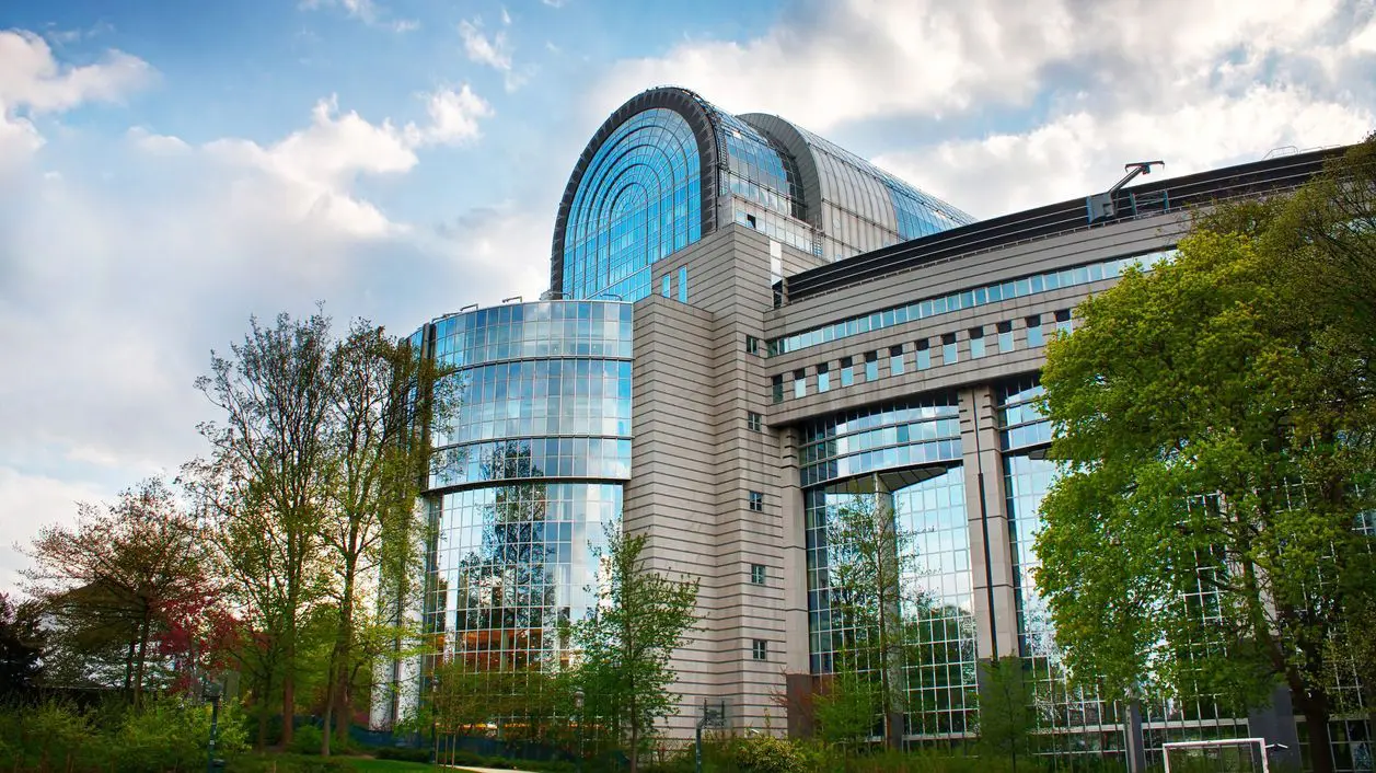 A modern building made of glass and steel, surrounded by trees.