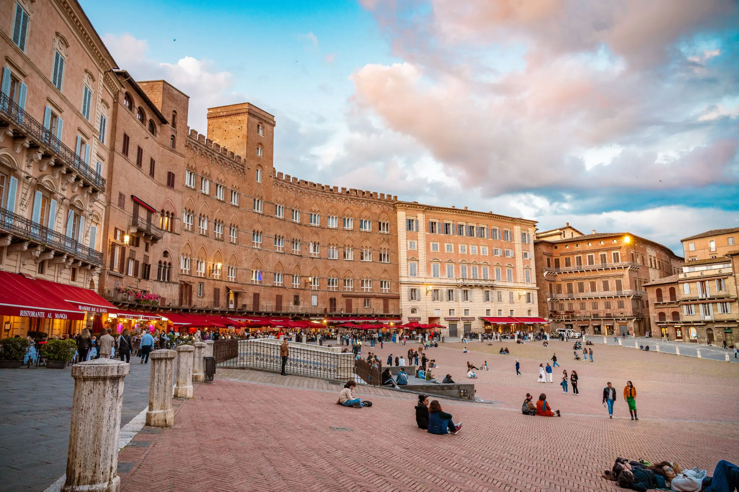 Piazza del Campo at sunset, with many people hanging out on the square. 