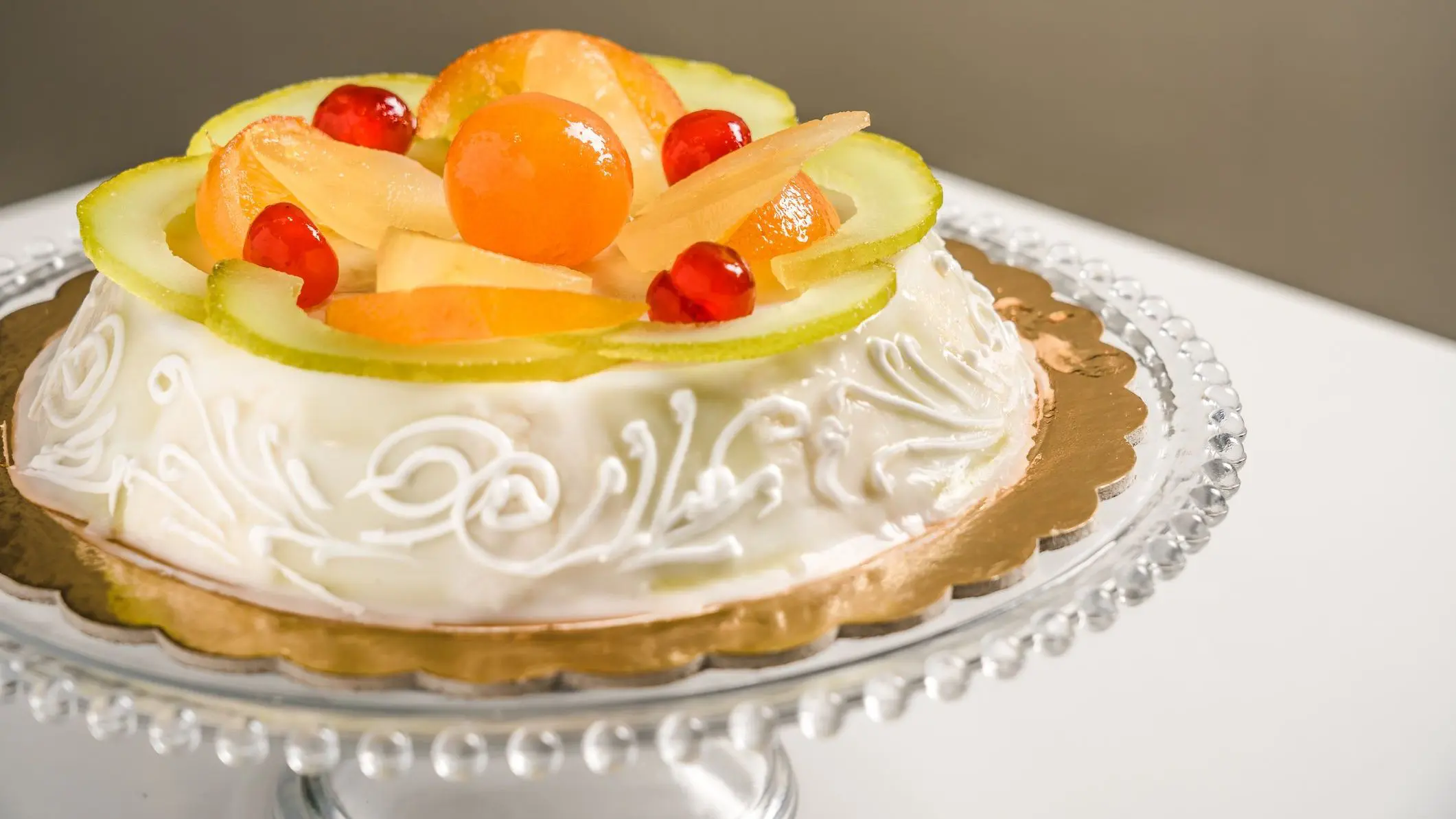 An elaborate Cassata Siciliana cake topped with large slices and pieces of candied fruit.