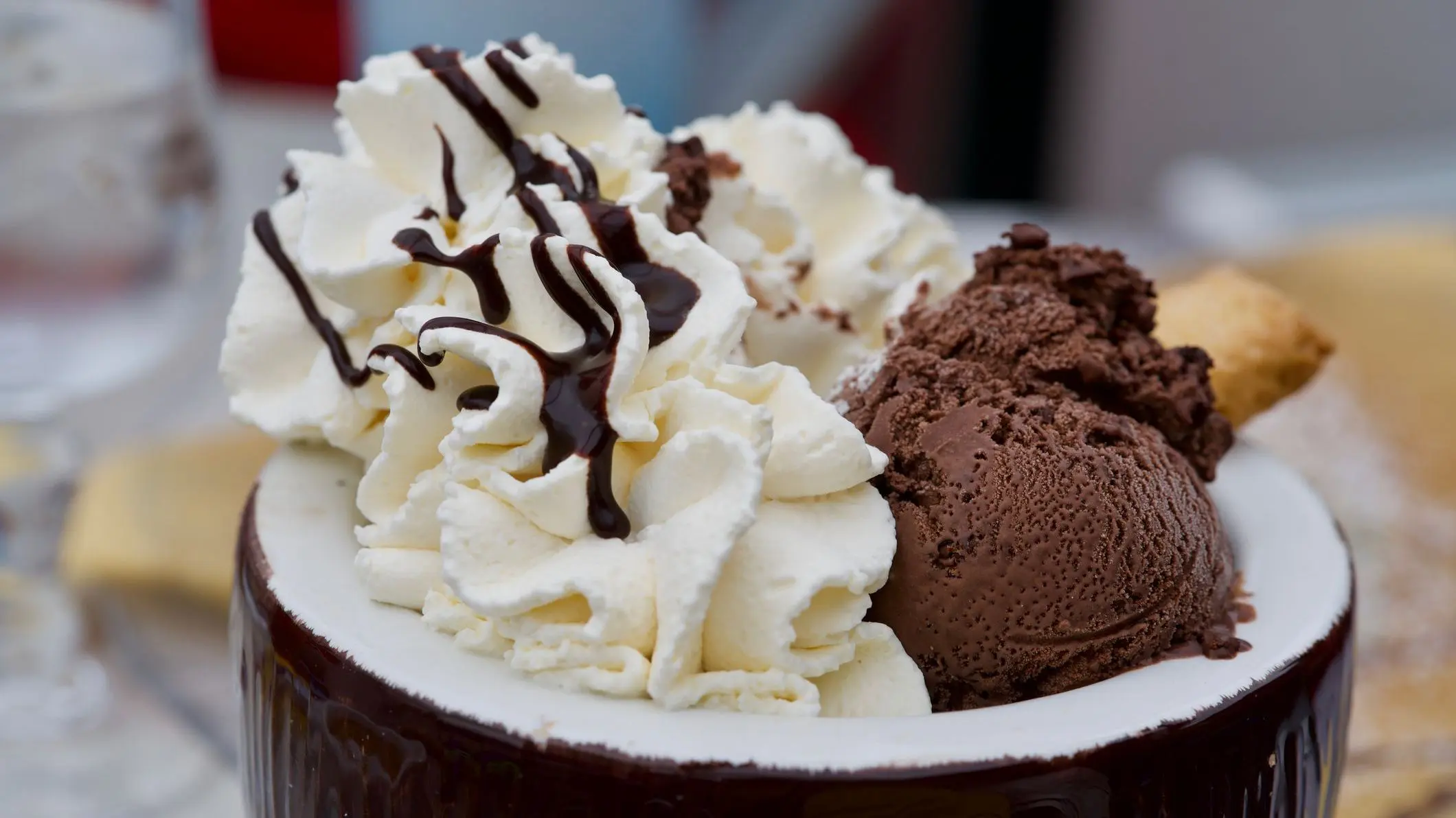 A large bowl filled with chocolate ice-cream and whipped cream topped with chocolate syrup.