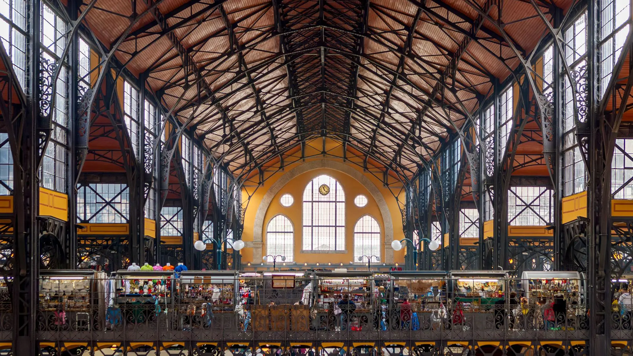 The interior of the market hall in Budapest with several stalls under an elaborate metal roof.