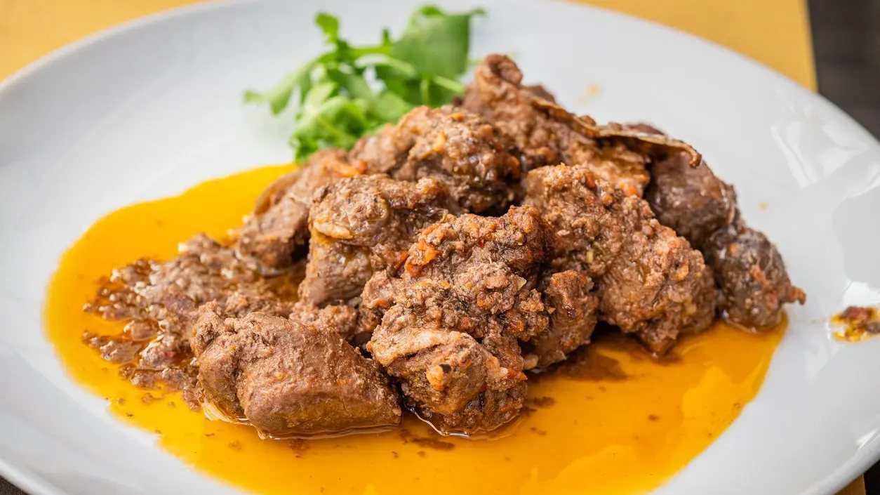A white plate with slow-cooked wild boar.