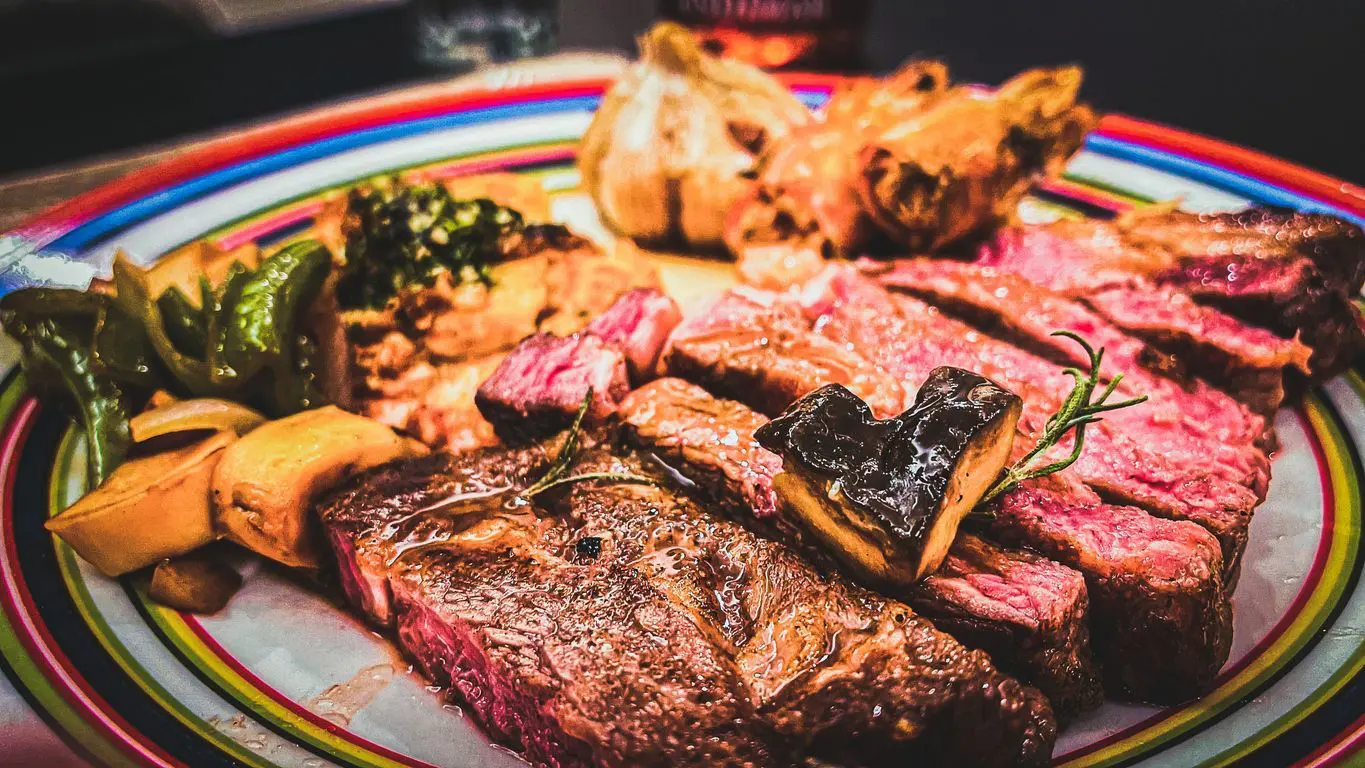 A close-up shot of a Bistecca alla Fiorentina in a colorful plate on a table.
