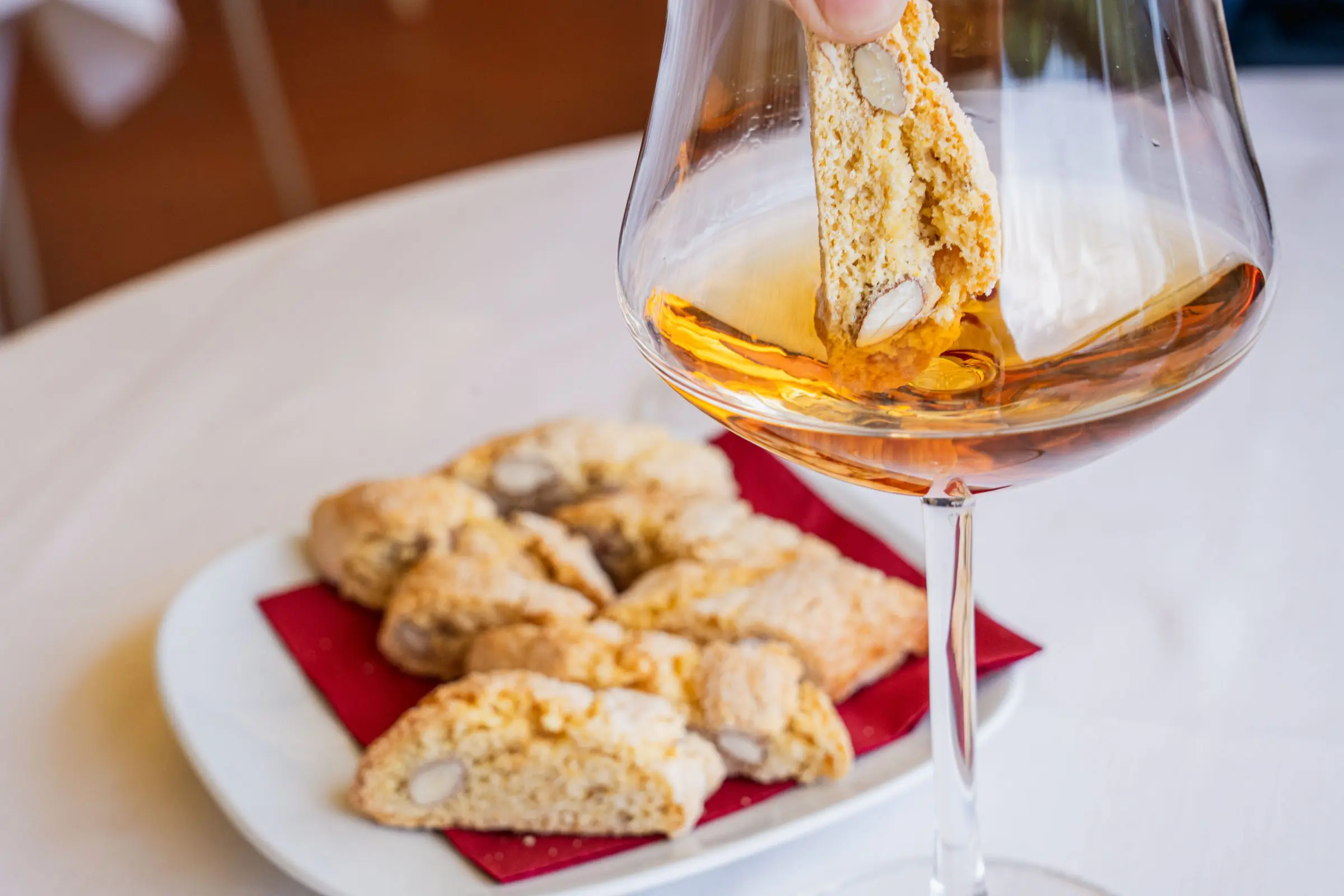 A small plate with cantucci and a glass of Vin Santo.