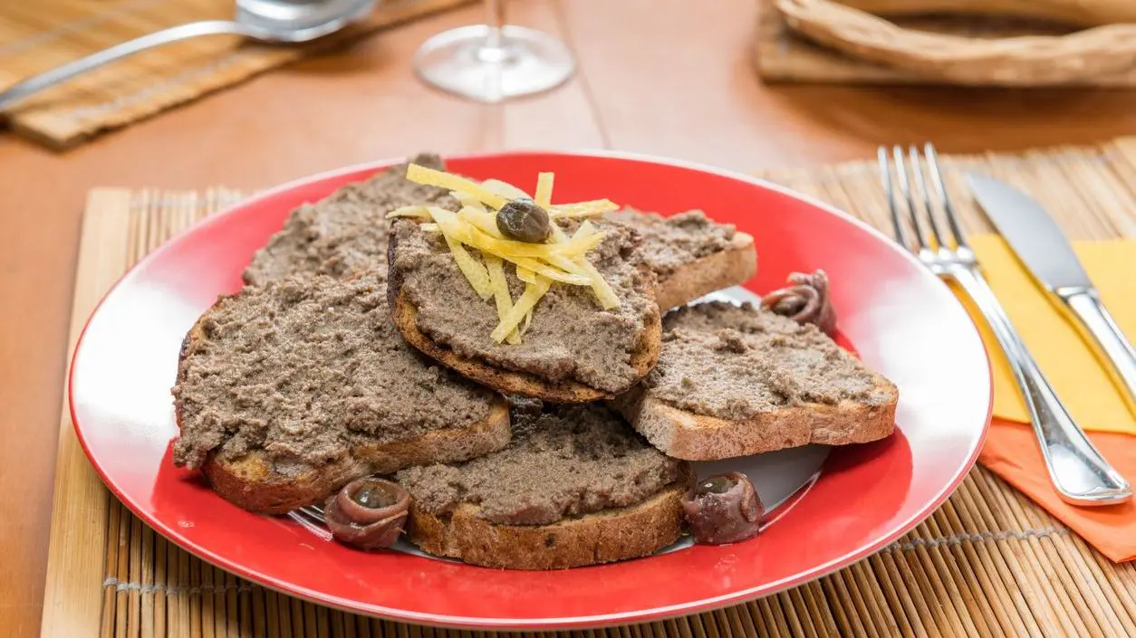 A red plate with slices of toasted bread topped with liver paté.