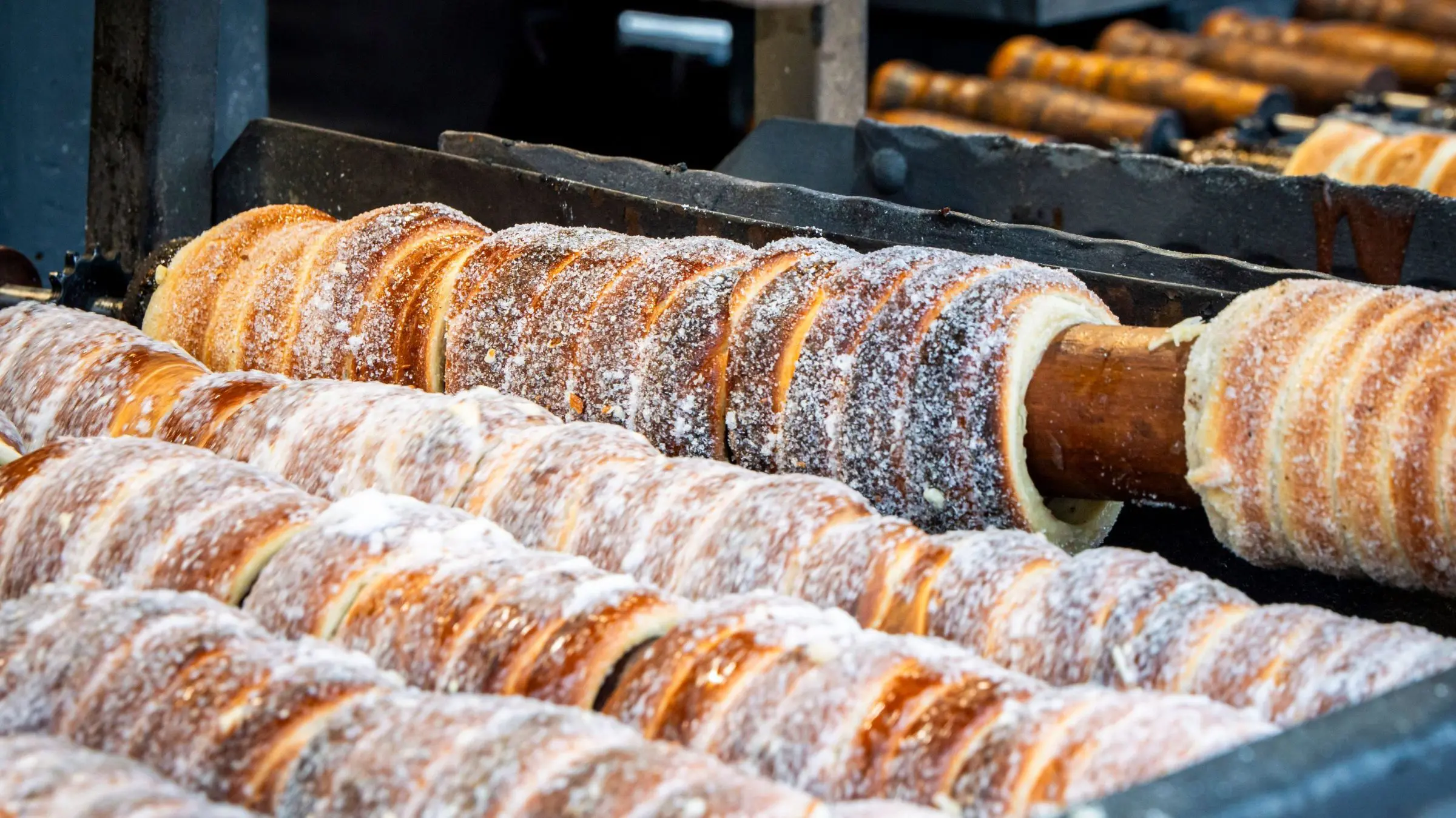 Fresh chimney cakes on spits over an open fire.