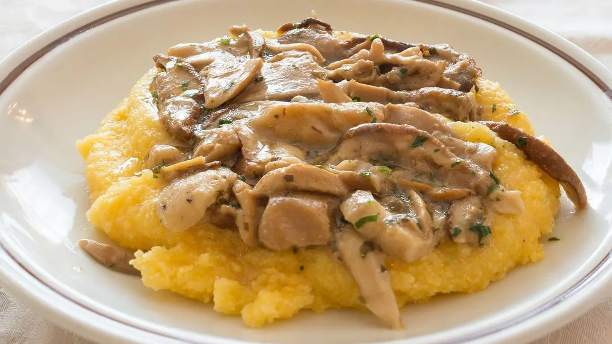 Creamy polenta topped with porcini mushrooms, the best food in Tuscany for a hearty vegetarian meal.