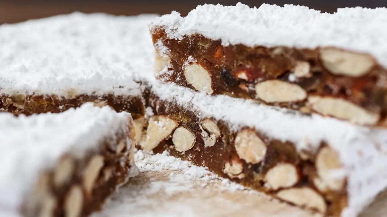 A close-up of Panforte, a cake filled with nuts and topped with icing sugar.
