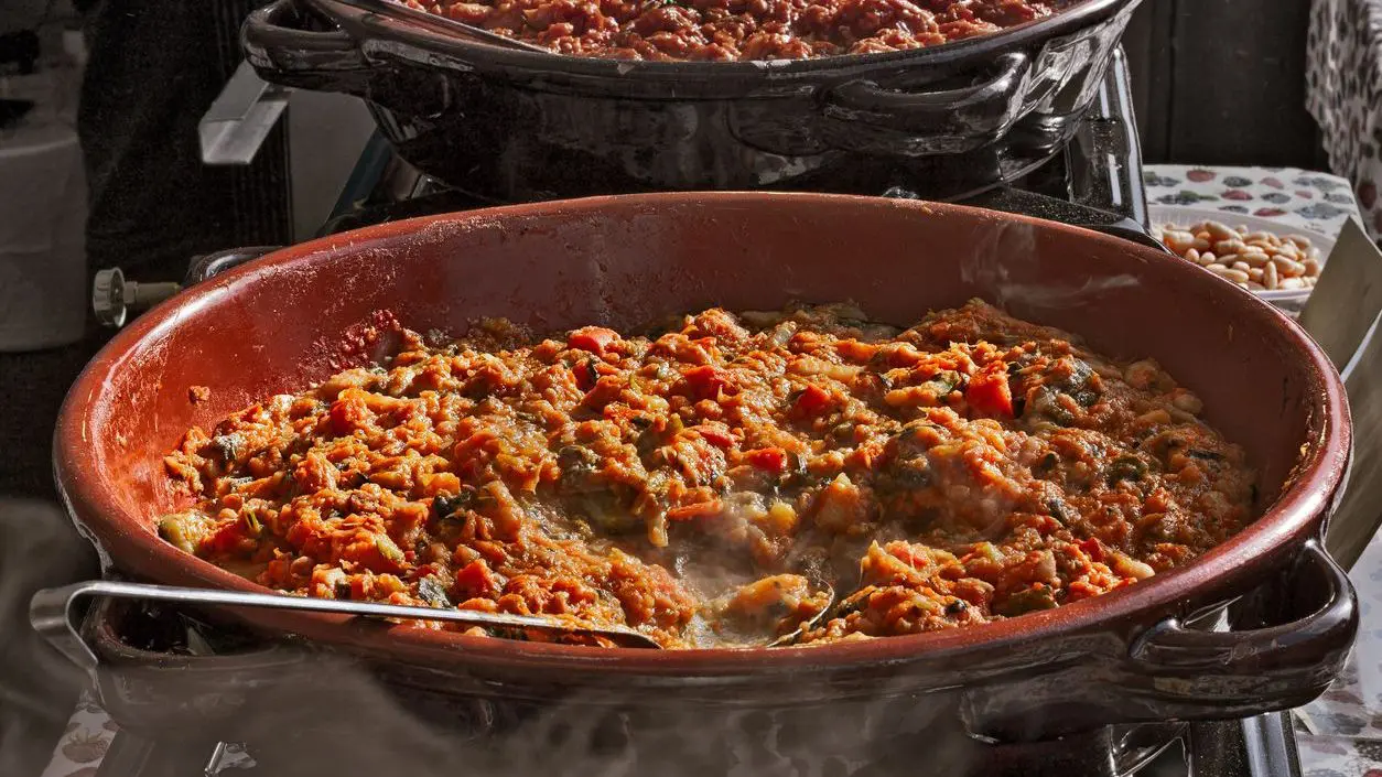 A large clay pot of ribollita, a traditional Tuscan soup made with black cabbage, bread, olive oil, beans, tomato and vegetables.