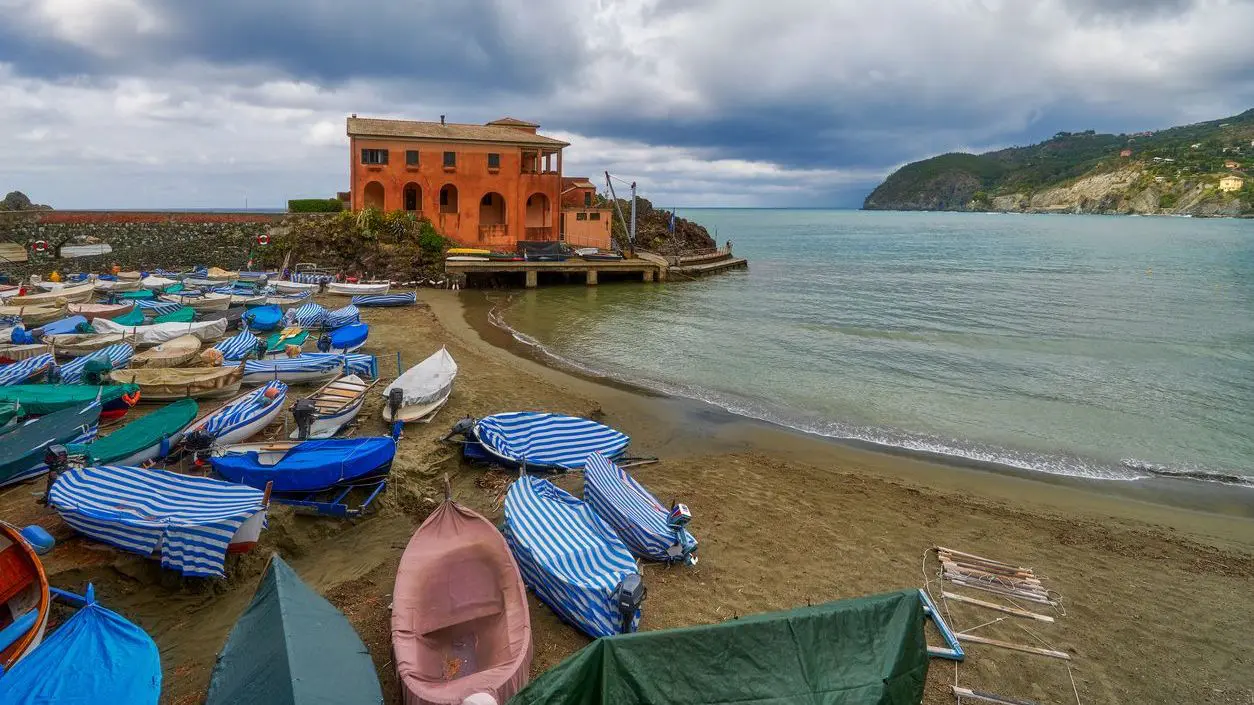 A sandy beach with many wooden boats on the shore and a beautiful building in the background. 