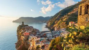 A panoramic view of the promontory upon which Vernazza is built, with the sea in the background and a hill in the foreground.