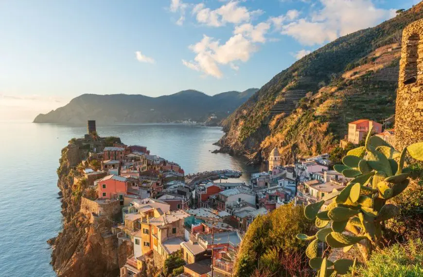 A panoramic view of the promontory upon which Vernazza is built, with the sea in the background and a hill in the foreground.