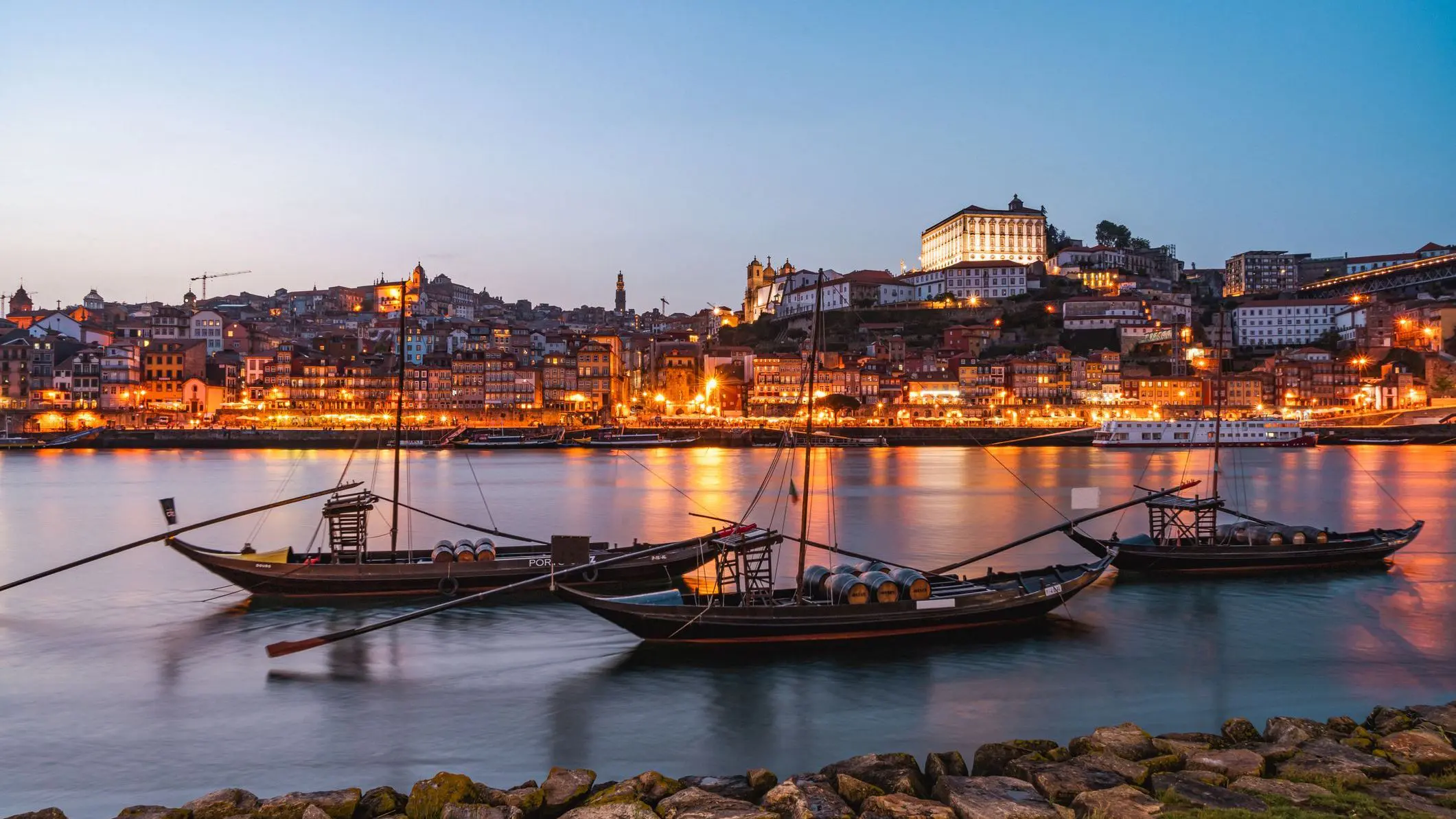 Traditional boats on the Douro River with the illuminated Porto in the background. 