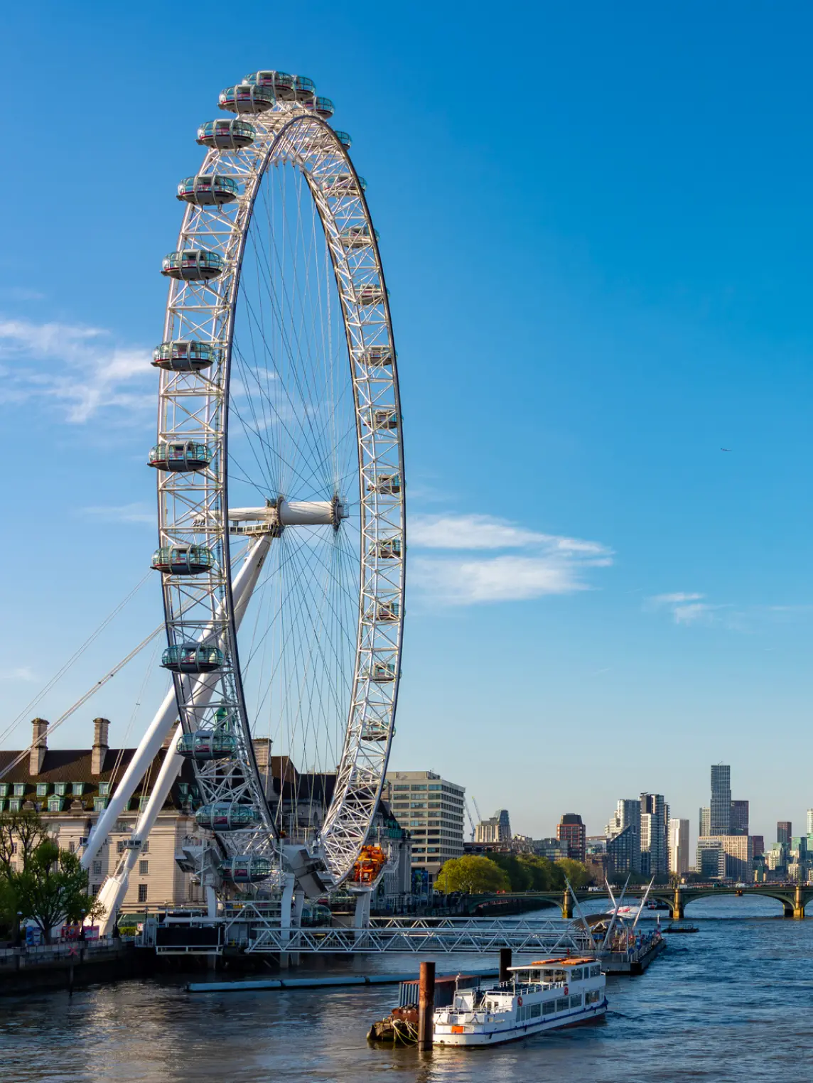 The London Eye observation wheel with its white circular structure and glass capsules overlooking the River Thames