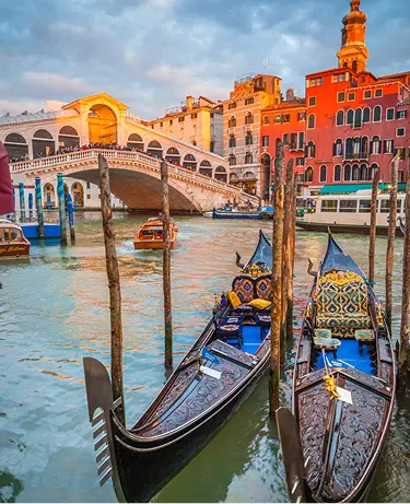 Classic panoramic view with traditional Gondolas on famous Canal Grande with famous Rialto Bridge in the background in beautiful golden evening light at sunset in summer, Venice, Italy