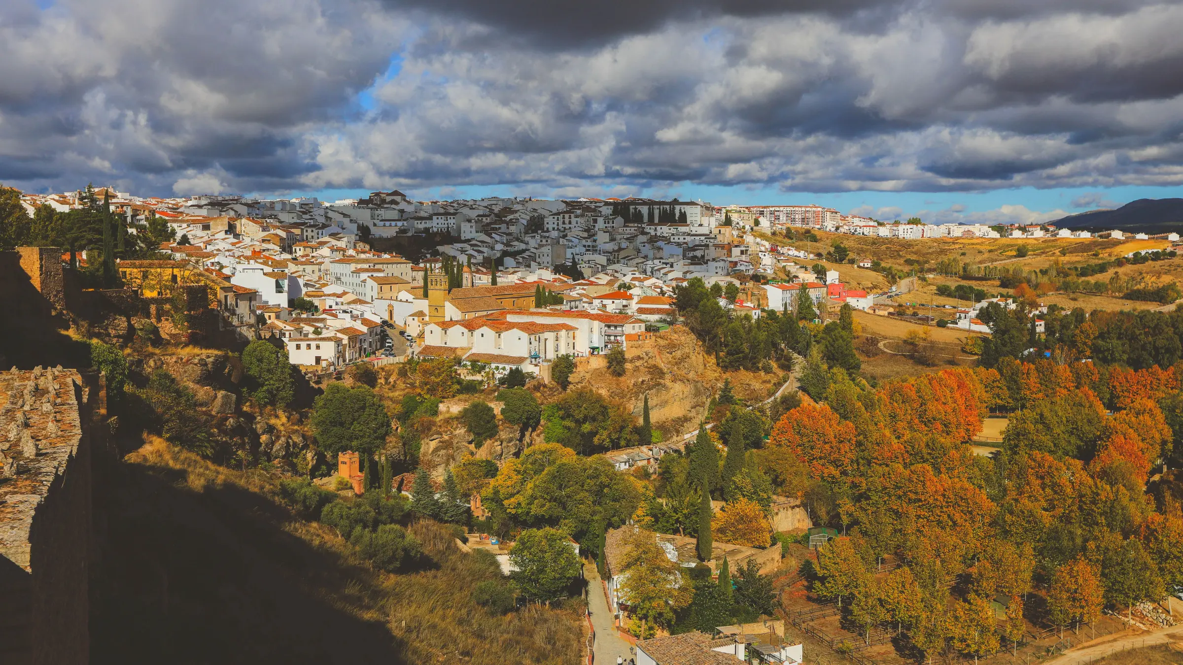 A panoramic view of a white village surrounded by trees with fall foliage. 