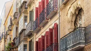 A close-up of elaborate balconies with red shutters in Malaga, Spain.