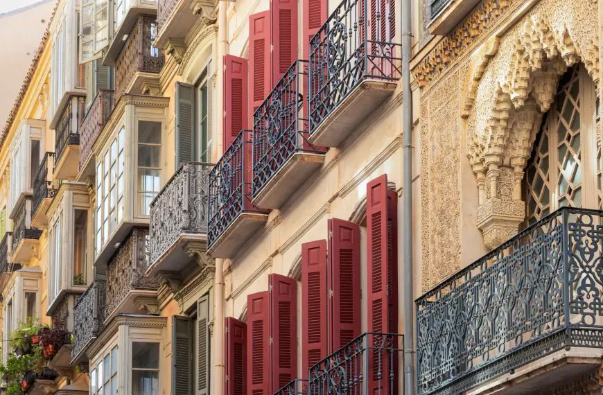 A close-up of elaborate balconies with red shutters in Malaga, Spain.
