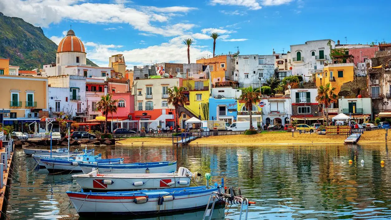 Colorful buildings along the shore and traditional wooden boats floating on the calm waters.