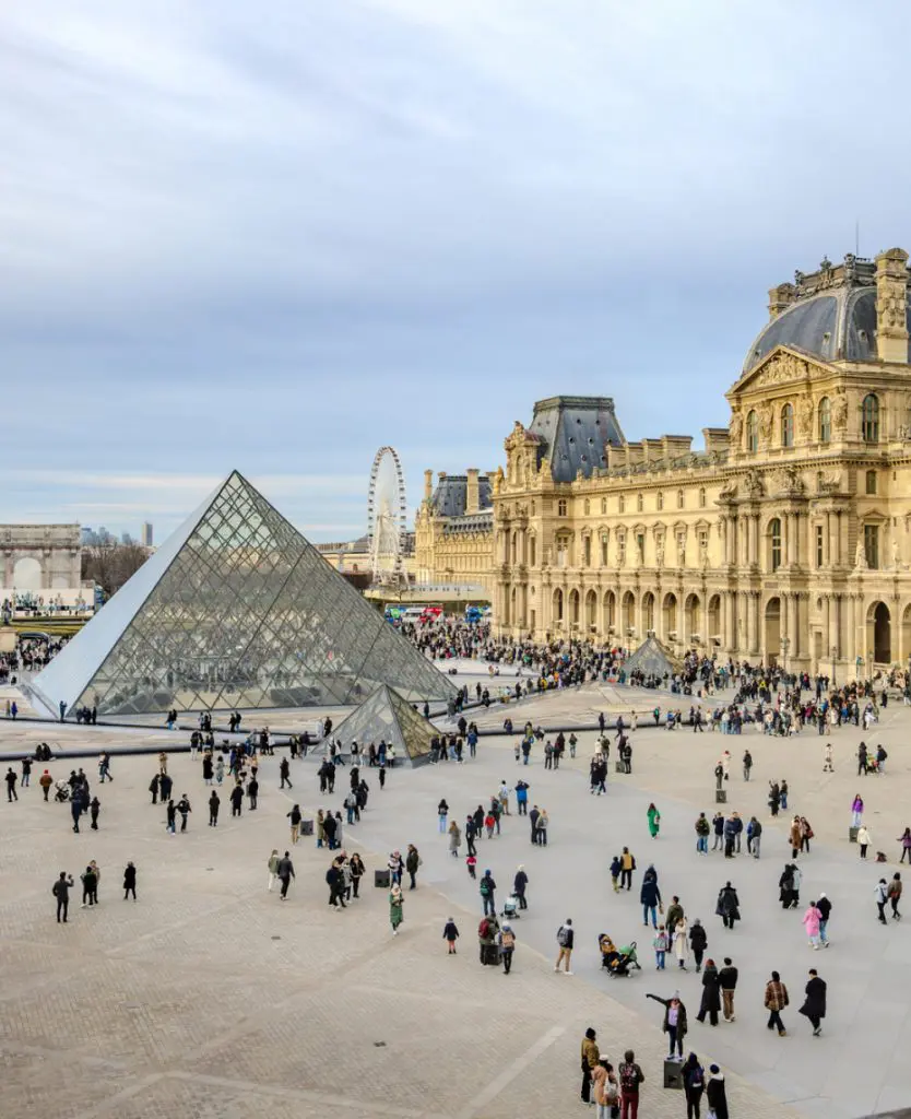 The Louvre Museum in Paris with its iconic glass pyramid in the central courtyard surrounded by historic architecture