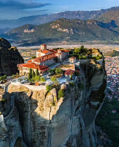 Rock formations and cliffside monasteries in Meteora rising above the Thessalian plains under a clear sky.