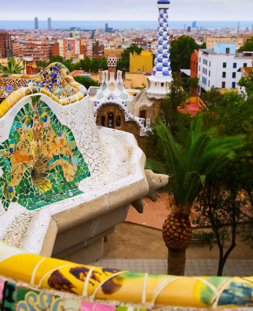 Colorful mosaic architecture and curving forms at Park Güell in Barcelona with views over the city skyline.