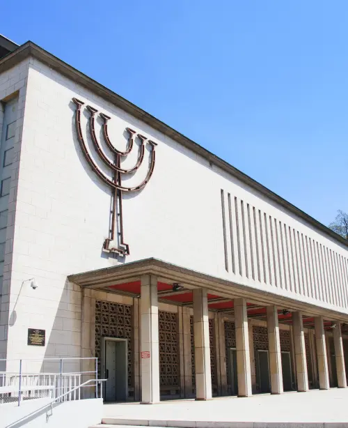Exterior view of the Synagogue de la Paix in Strasbourg, featuring modern stone architecture, large arched windows, and a minimalist façade.