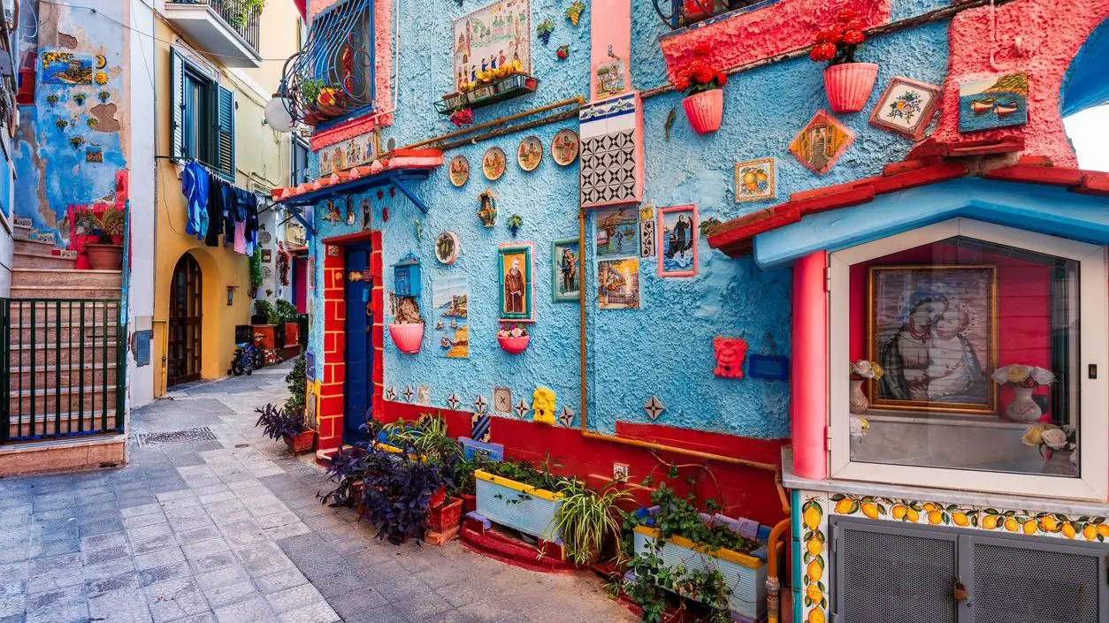 A cobbled street with its blue-painted walls decorated with ceramics. 
