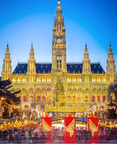 Festive European Christmas market with illuminated wooden stalls, holiday decorations, and crowds browsing seasonal gifts at night.