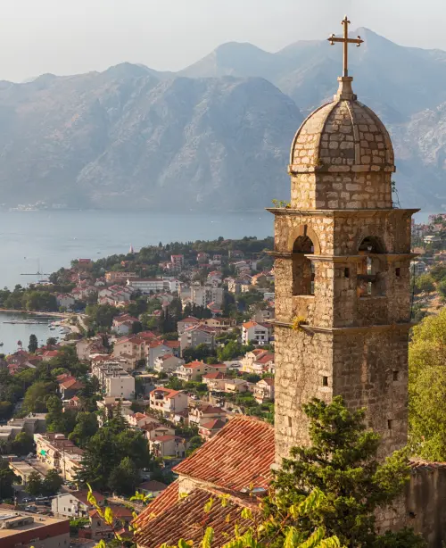 Historic old town of Kotor nestled between mountains and the Adriatic Sea, with stone buildings and fortified walls.
