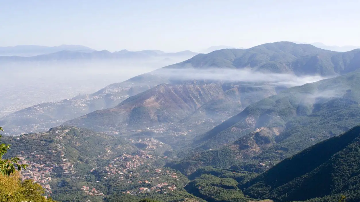 A panoramic view of a green mountain dotted with small villages. 