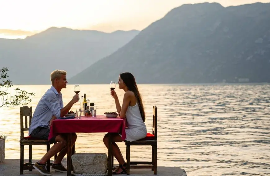 A young couple enjoying a sunset dinner by the sea or a lake.