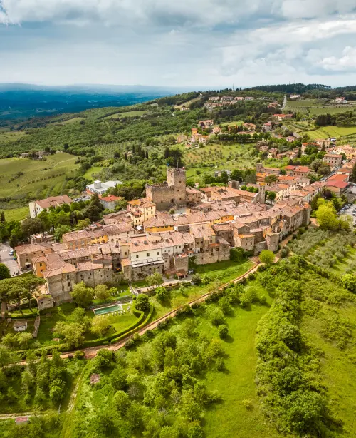 Peaceful landscape in Tuscany, Italy featuring sunlit vineyards, stone villas, and soft rolling green hills.
