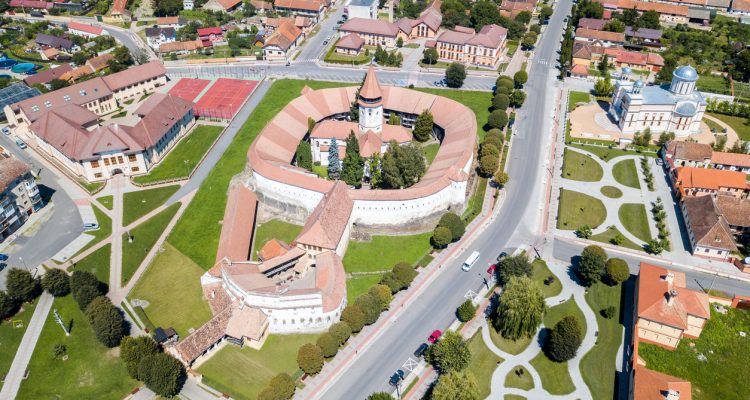 Prejmer Fortified Church, Brasov County, Transylvania, Romania. Aerial view. Medieval fortress with a church, clock tower, high spire, thick walls, red tiled roofs, surrounded by a town