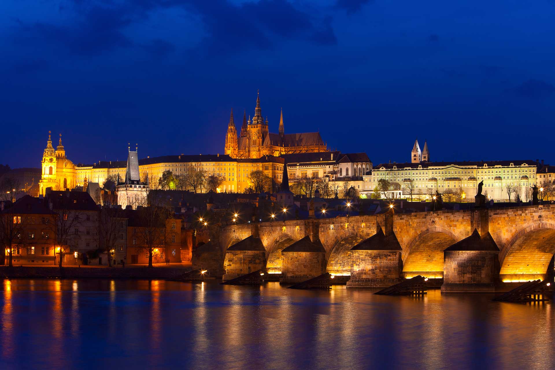 An evening shot of Prague Castle with Charles Bridge in the foreground. Many fall festivals in Europe take place in Prague. 