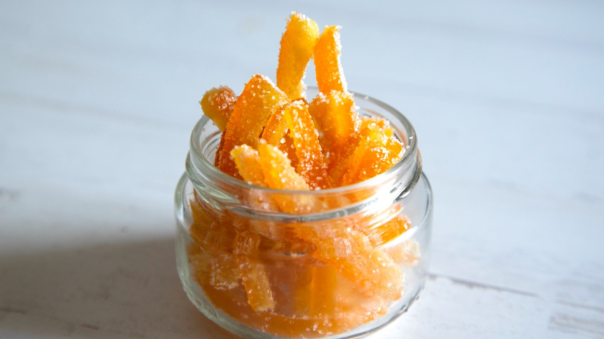 A jar filled with candied orange strips. 