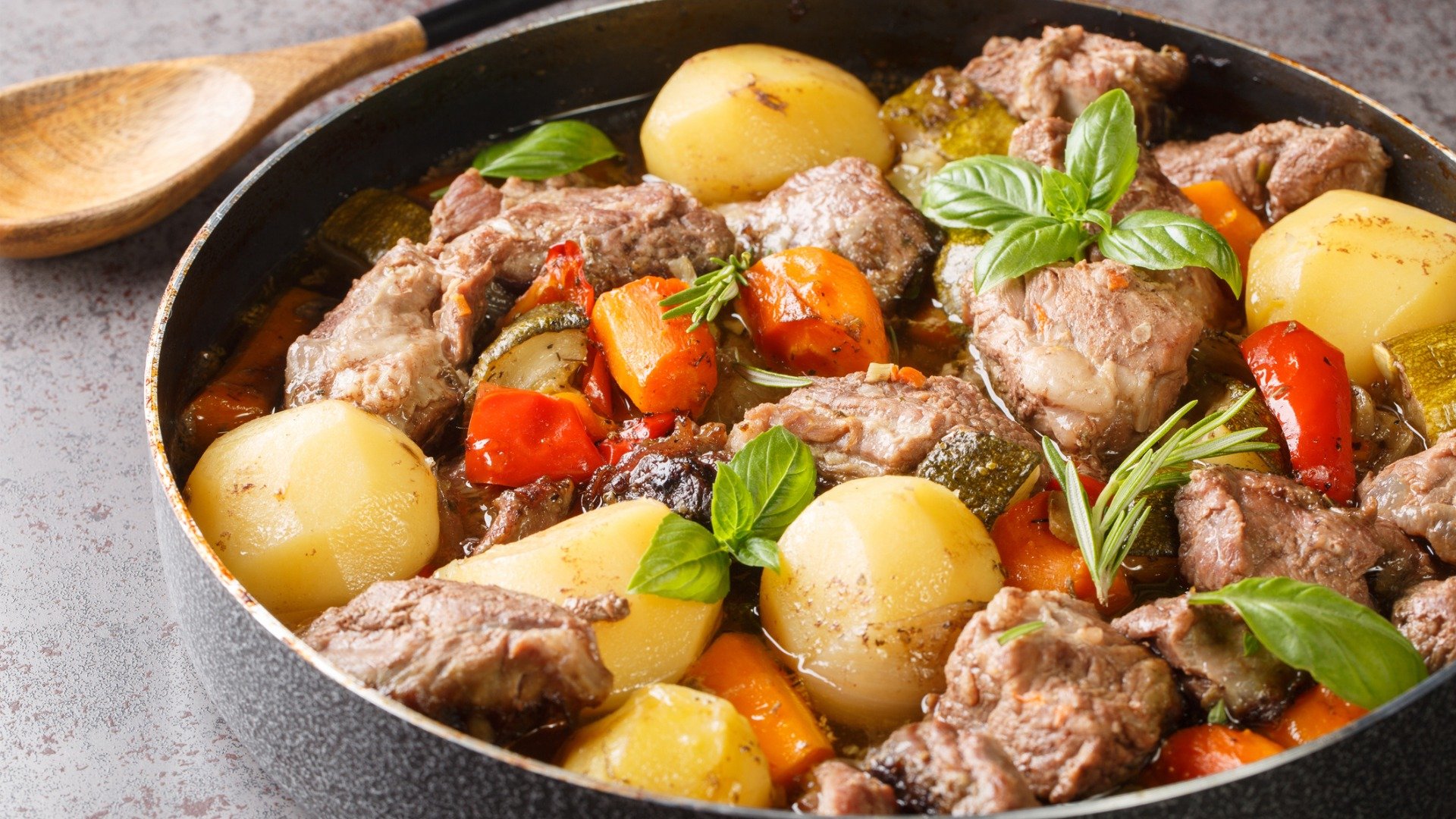 A baking pan filled with meat pieces, potatoes, and carrots. 