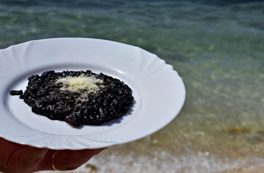 This is a close-up of a dish of black risotto in Croatia, with the sea as its backdrop. Croatian risotto is a local specialty you must try during your trip to Croatia.