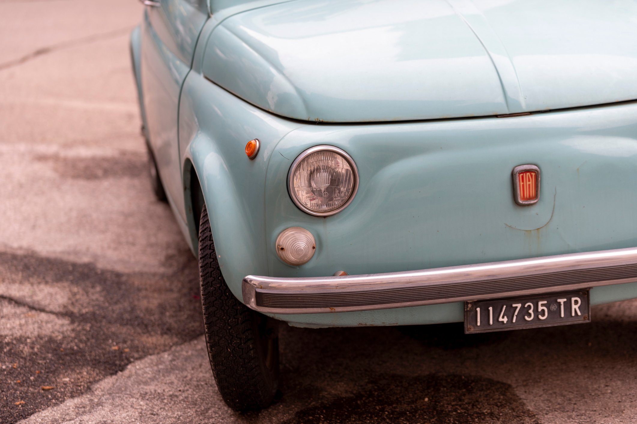 This is a close-up of a vintage light blue Fiat 500.