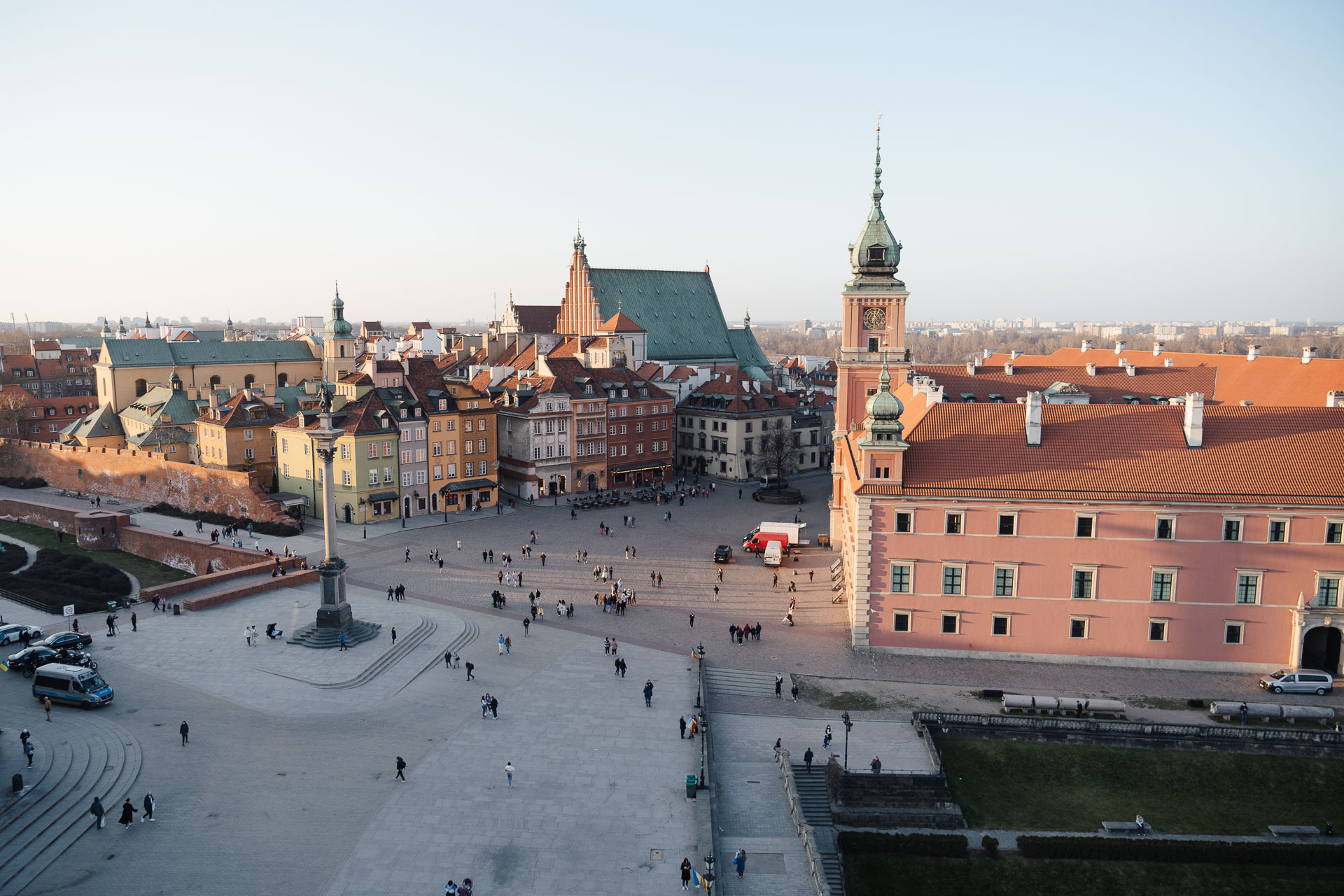 View from St Anne's Church Bell Tower in Warsaw, Poland. We see Castle Square from above with the Old Town in the background. Prominent structures are Sigismund's Column on the left and the Royal Castle on the right. The scenery is washed in golden hour light.