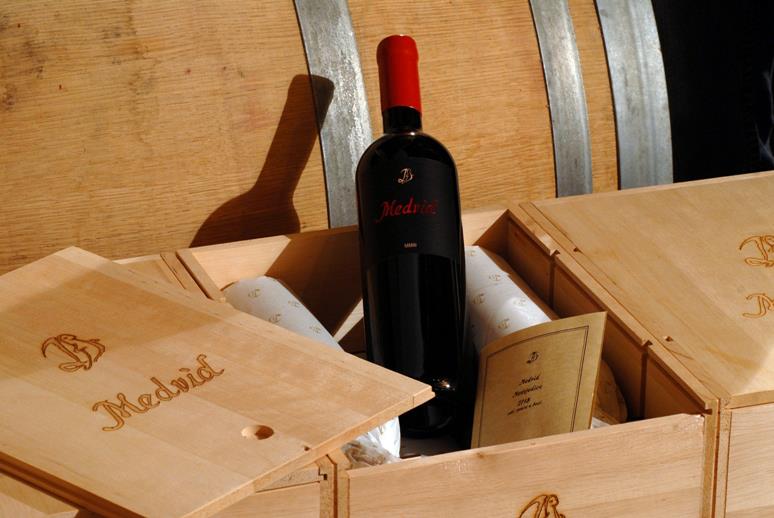 This image shows a bottle of Medvid wine emerging from a wooden box.