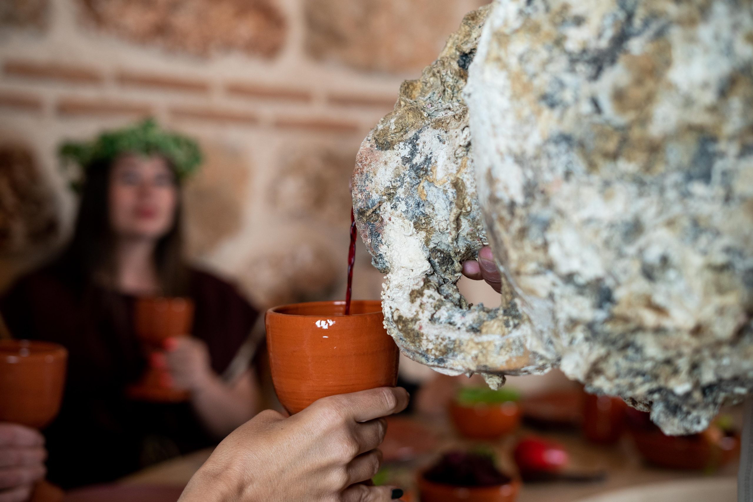 This image shows someone pouring wine from an ancient-like amphora. 